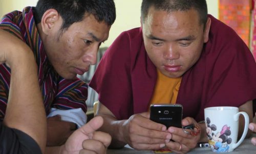 Bhutan: Mönch beim Daddeln