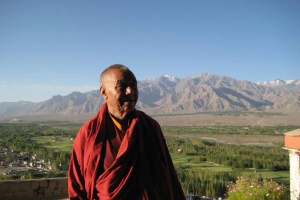 Mönch in Ladakh, im Hintergrund Felder und eine Gebirgskette