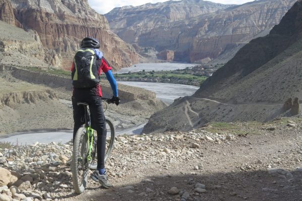 Nepal, Mustang per Mountainbike. Mountainbiker genießt den Blick auf die Felsformationen im Kali-Gandaki-Tal.